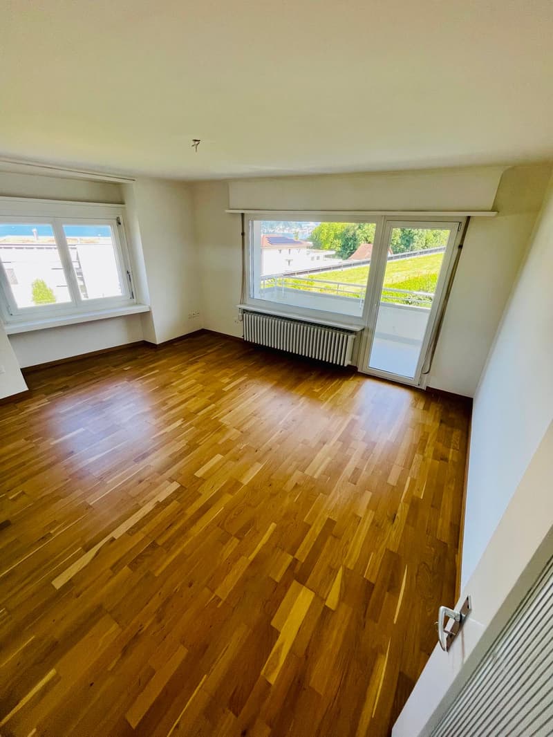 empty room, wooden floor, white walls, two windows, balcony, radiator