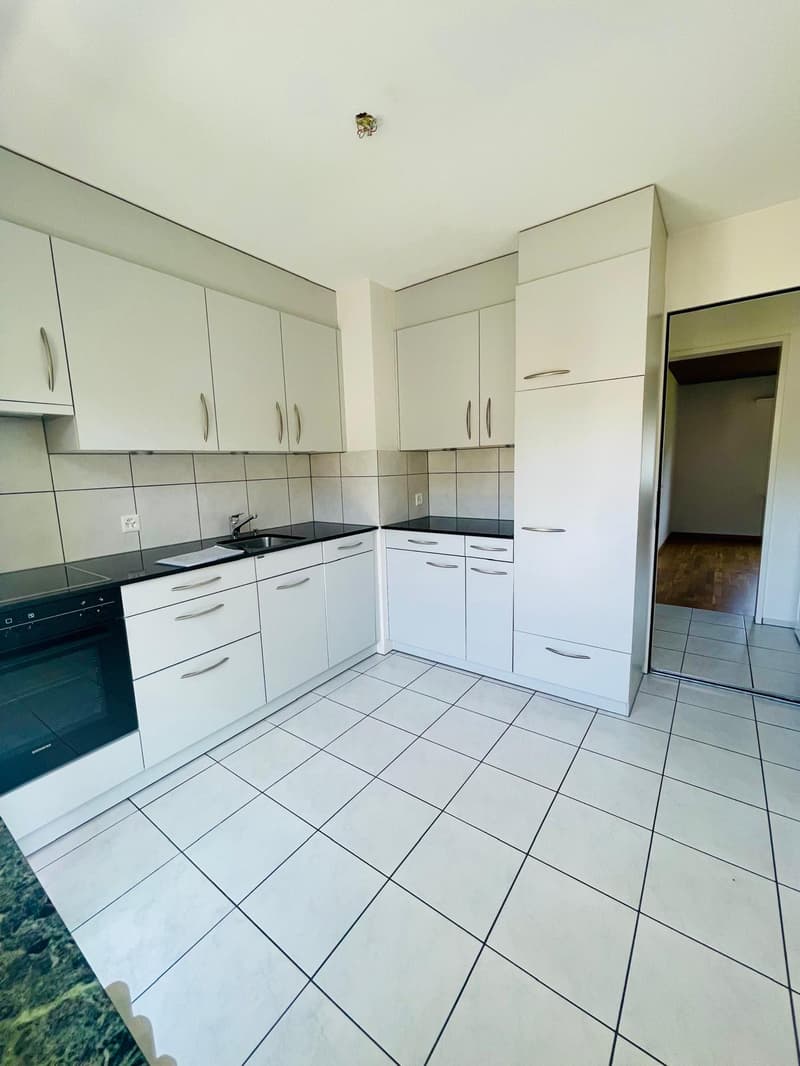 modern kitchen with white cabinets, black countertops, white tiled floor, stainless steel sink, oven, dishwasher, washing machine