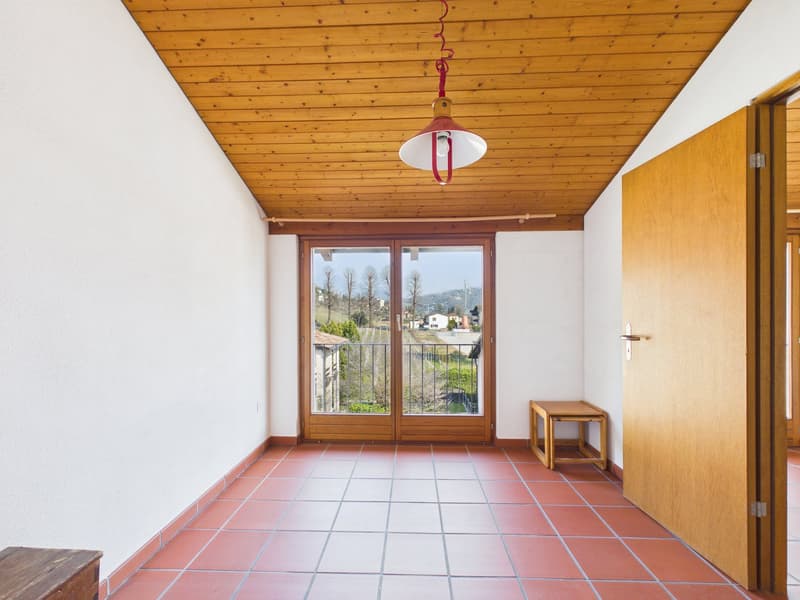 Empty room, wooden ceiling, red tiled floor, sliding glass doors with balcony, wooden table, white walls