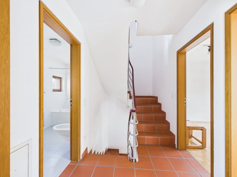 White walls, orange tiles, spiral staircase, two wooden doors