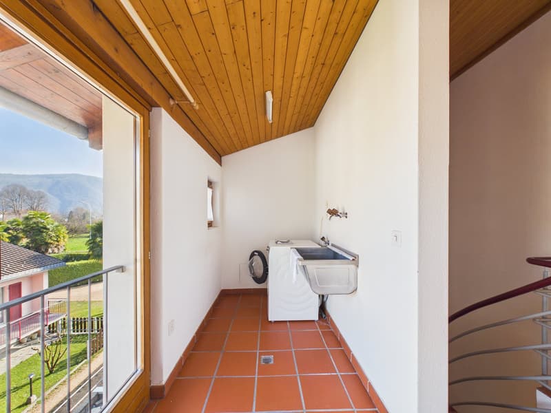 Washing room with private washing machine, balcony with sliding door, tiled floor, sink, washer, spiral staircase to other floors