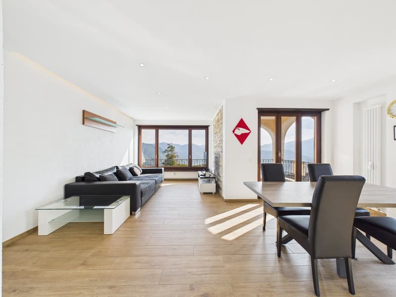 modern living room with wooden floor, white walls, black couch, glass table, dining table, large windows, balcony, mountains view