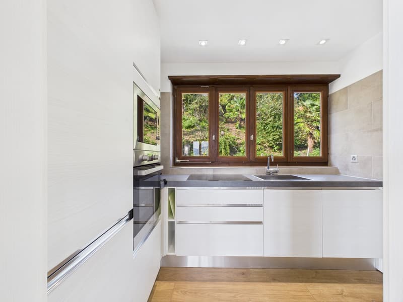modern kitchen with white cabinets, granite countertop, stainless steel appliances, large window with view