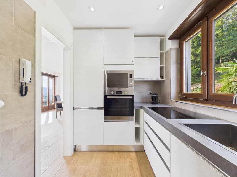 modern kitchen with white cabinets, wooden floor, stainless steel appliances, granite countertops, double sink, large window with view