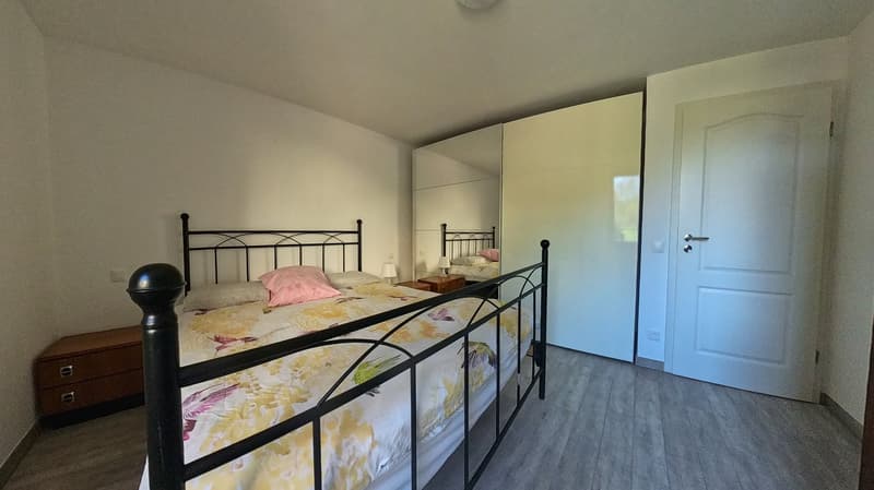 Bedroom with a double bed, nightstands, a large mirror, and a wooden cabinet.