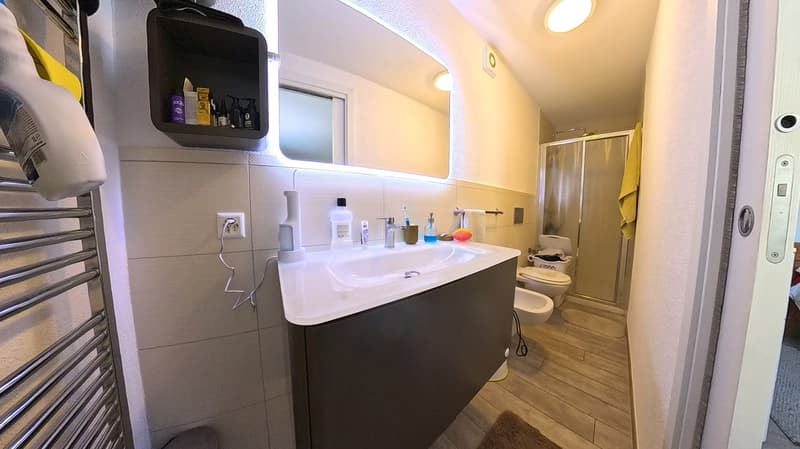 Bathroom with sink, mirror, toilet, shower, towel rack, power outlet, and towel
