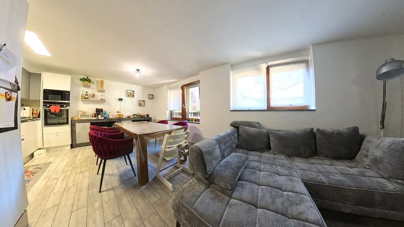 Open plan living room and kitchen, wooden table, gray sofa, kitchen appliances, dining chairs, floor lamp