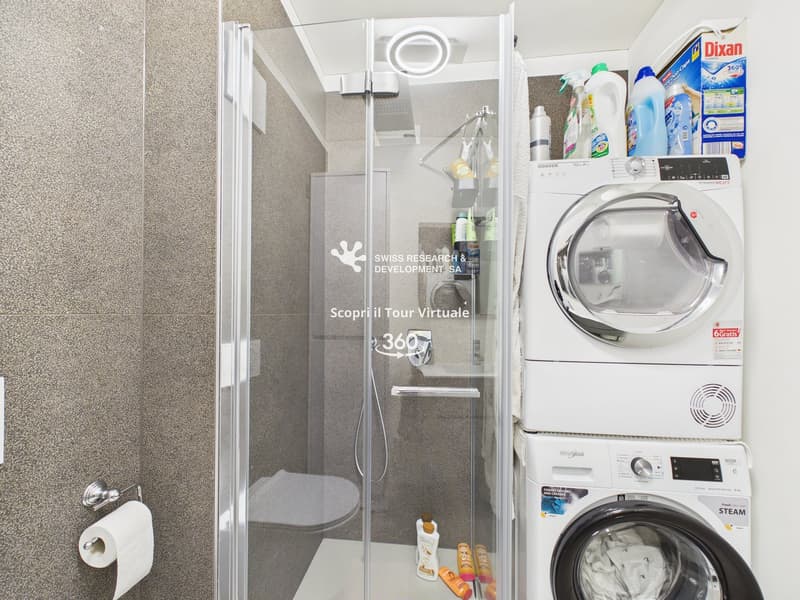 Laundry room with a glass shower, toilet, and stacked washing machines