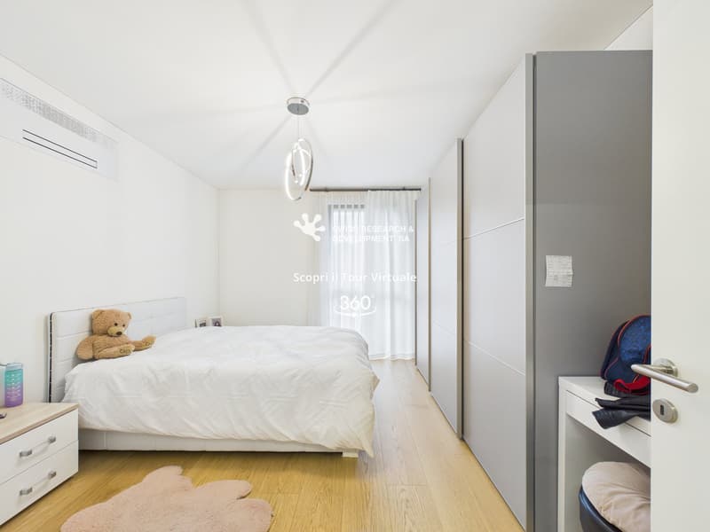 Bedroom with bed, white walls, wooden floor, white headboard, white bedspread, white nightstand, white drawers, white wardrobe, white curtains, white ceiling light, teddy bear, rug, backpack, and a bottle