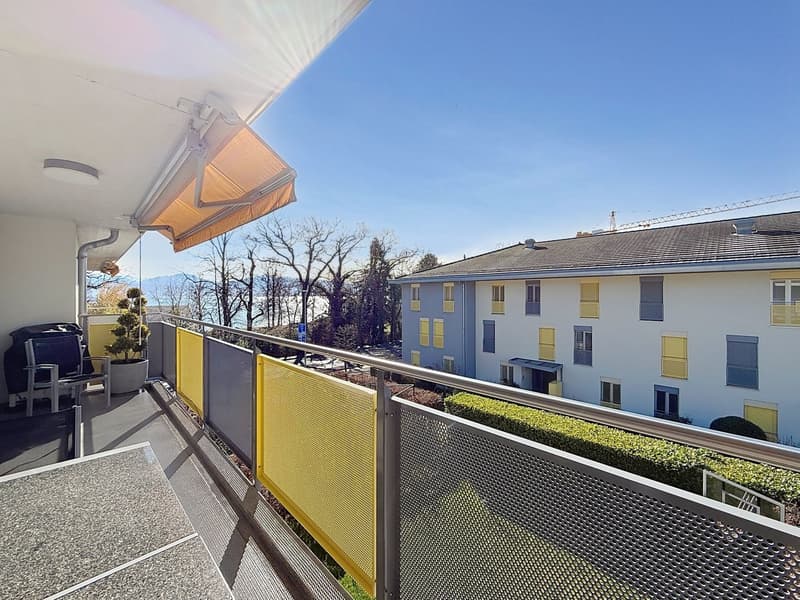 Balcony with yellow railings, metal mesh, and a view of the city and mountains
