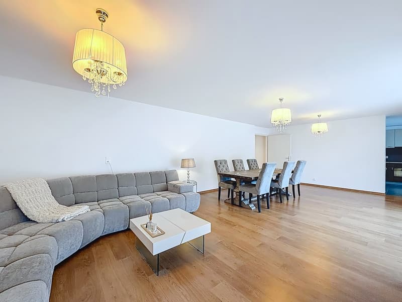modern living room with wooden floor, gray sofa, white coffee table, dining table with chairs, chandeliers, lamps