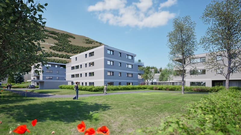 A modern, multi-story apartment building with a gray exterior and large windows. The building is surrounded by a grassy area with trees and flowers in the foreground.