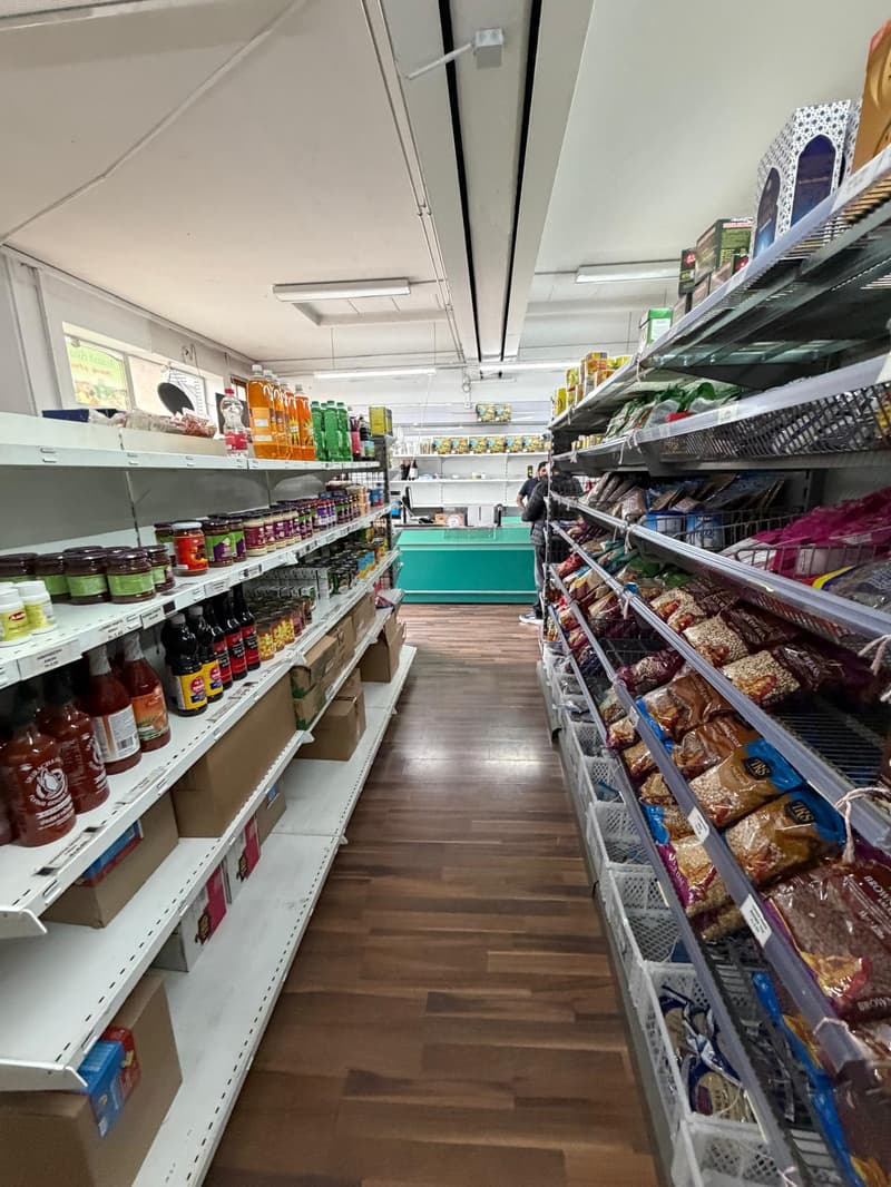aisles of store with shelves full of products, wooden floor, fluorescent lighting