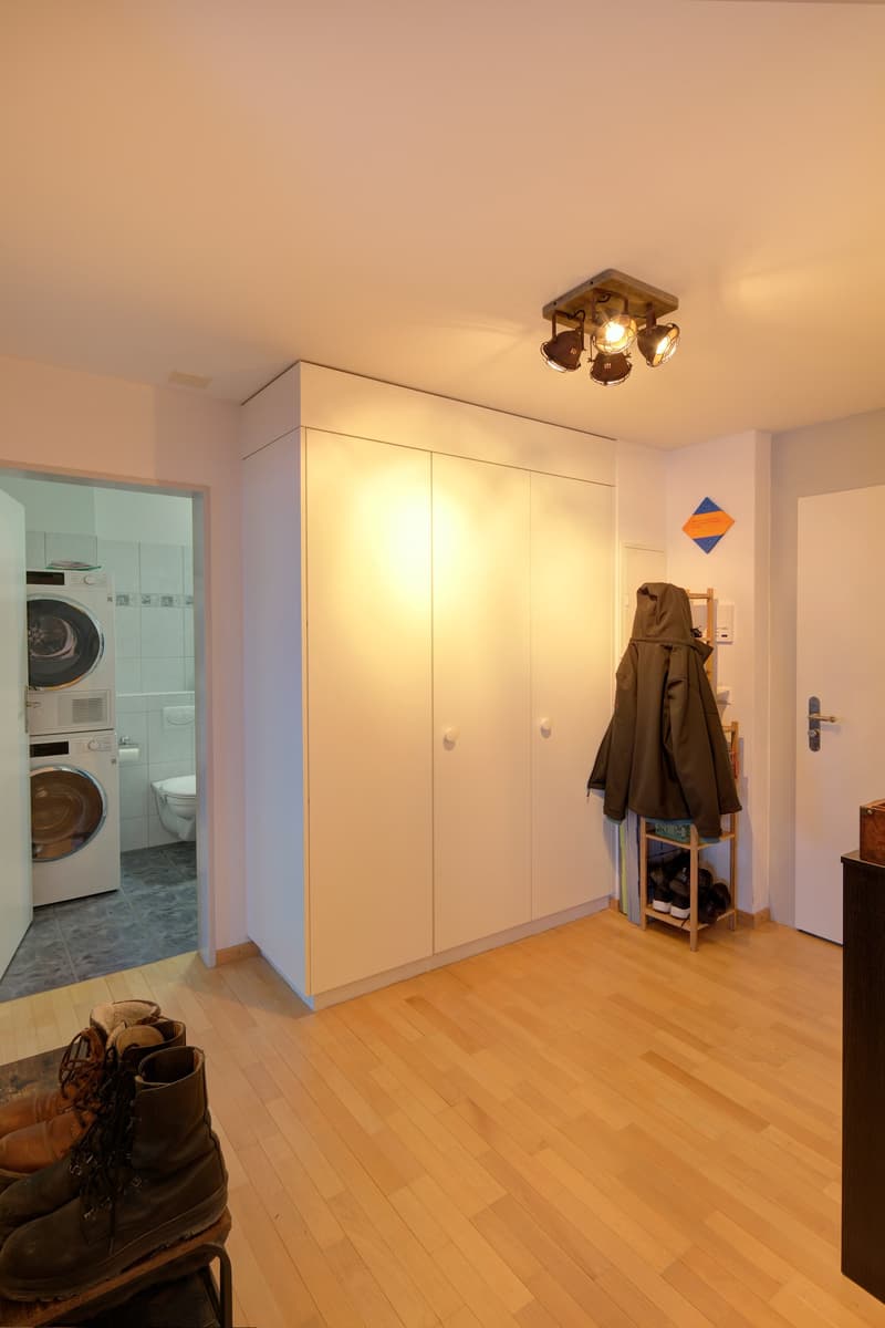 Entryway with shoe rack, washing machines, coat, wooden floor