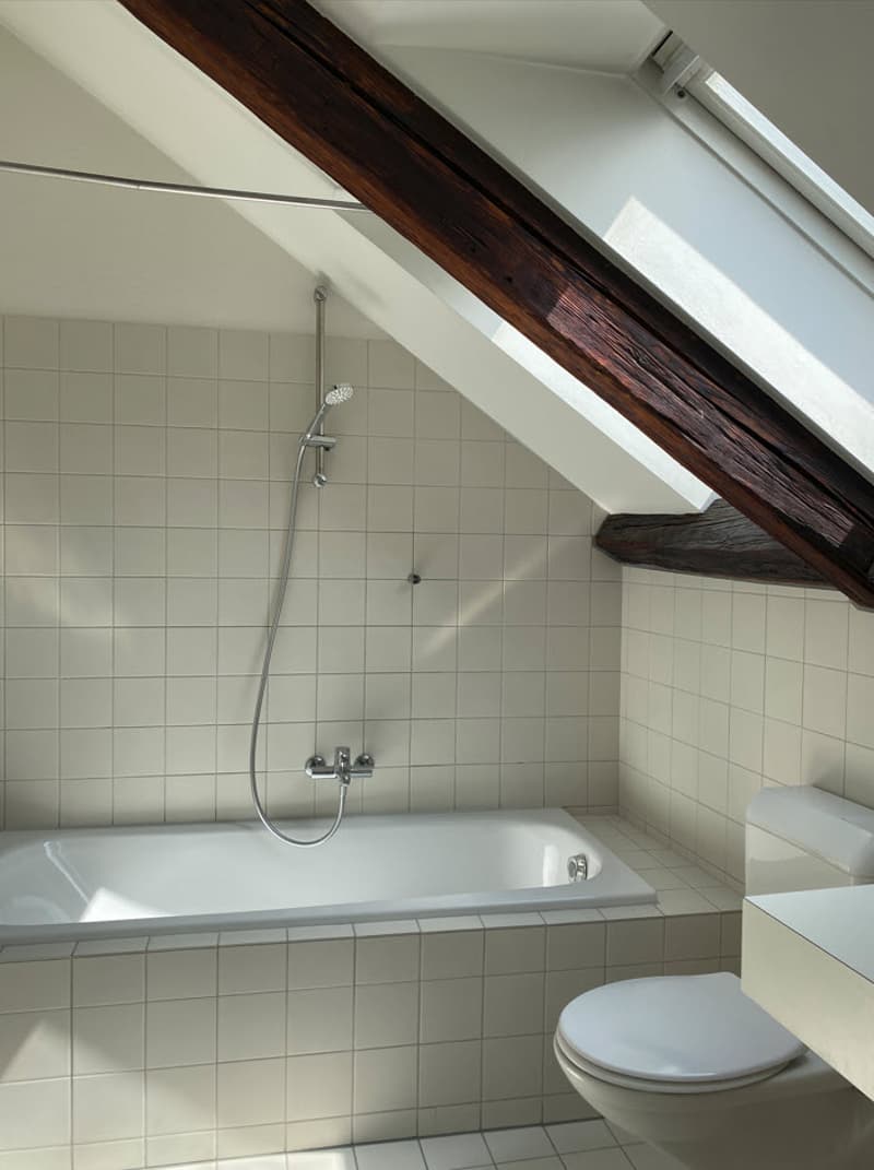 Bathroom with tiled walls, bathtub, shower, and exposed wooden beams on the ceiling