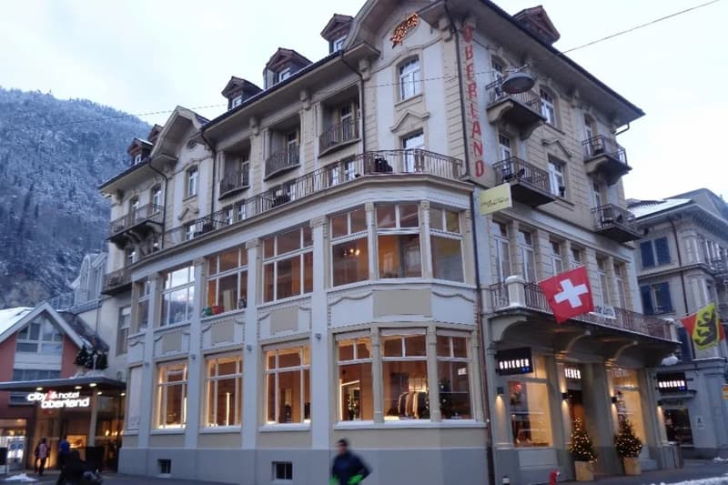multi-story building, arched windows, balconies, storefront with displays, Swiss flag