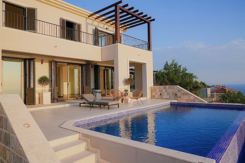 3 story house with a balcony, swimming pool, lounge chairs, table, plants