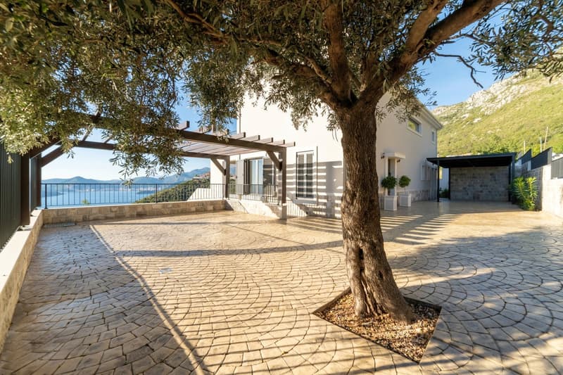 stone paved terrace, tree, balcony, white house, coastal mountains in the background