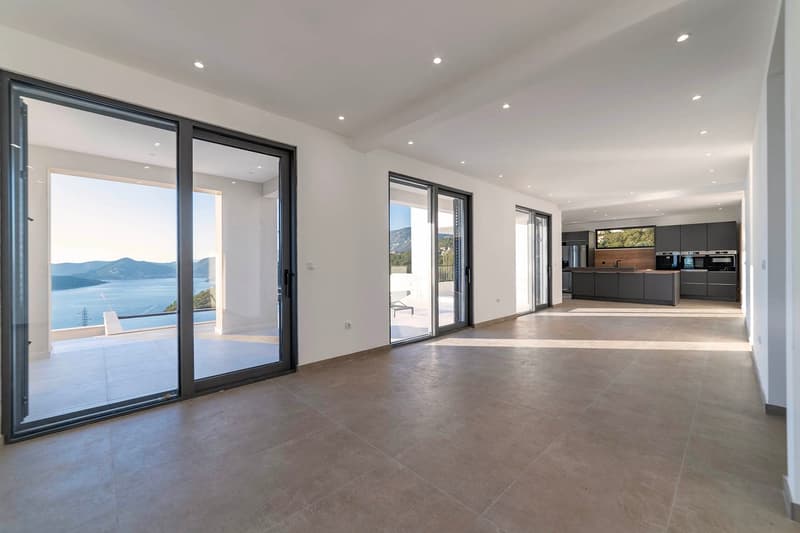 open plan living room, large sliding glass doors, modern tile flooring, open kitchen, balcony with sea view