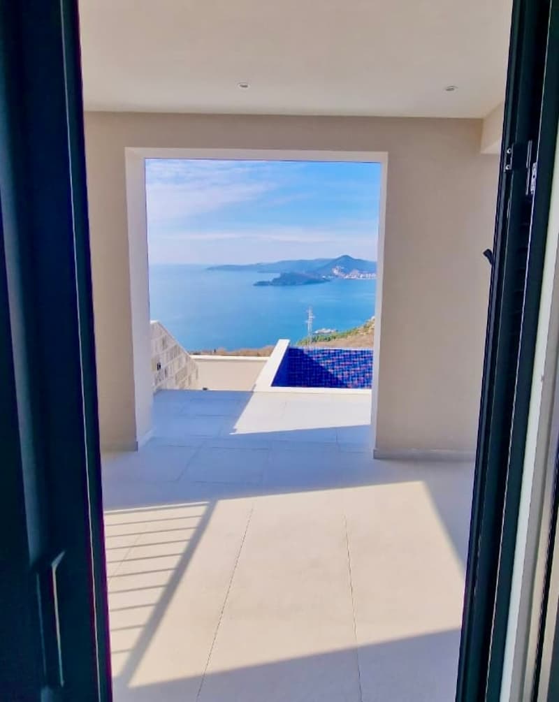 large balcony with blue swimming pool, ocean view, open doors