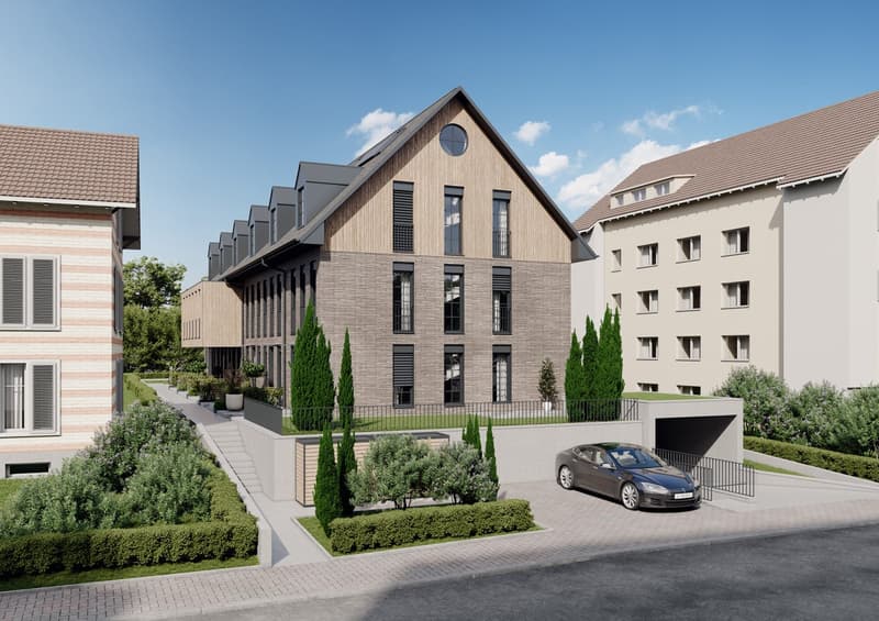 3-story apartment building with a modern, wooden and brick facade. The building has large windows and a circular window at the top. There is a Tesla electric car parked in the driveway, and the surrounding area is landscaped with trees and shrubs.