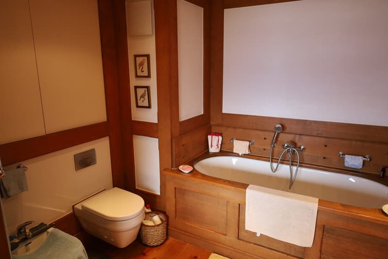 Wooden vanity with sink, toilet, towel rack, framed artwork on the walls