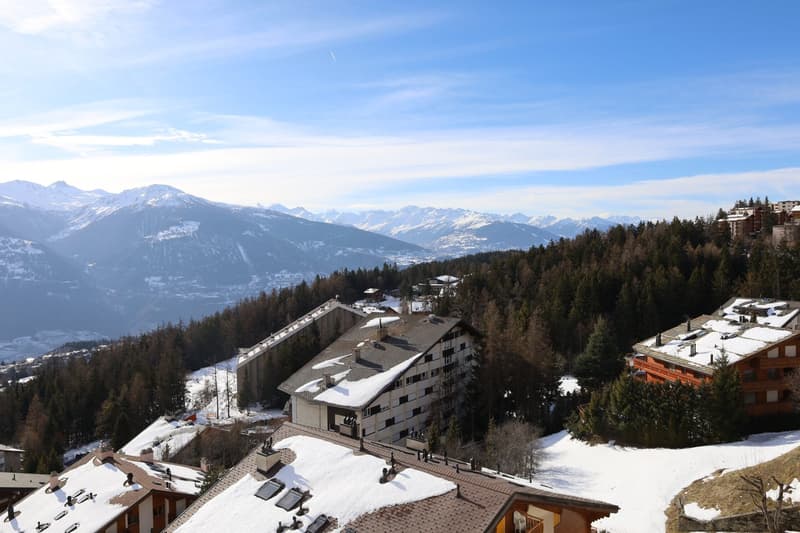 Condominium building with multiple floors surrounded by snow covered mountains