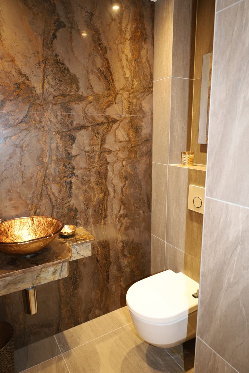 modern bathroom with brown marble tiles and white ceramic wall tiles, a bronze bowl, and a modern flush toilet