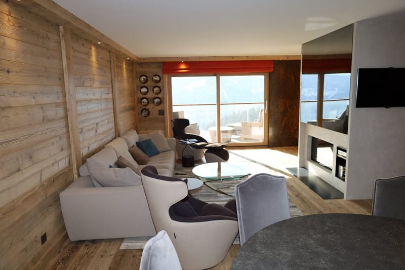 wooden walls, large sofa, armchairs, fireplace, large windows, television, coffee table, desk, chairs, table