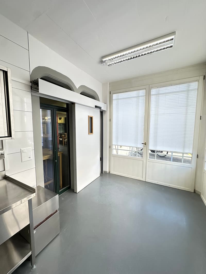 empty room, white walls, gray floor, a sliding door, a double door, a table and a bicycle outside