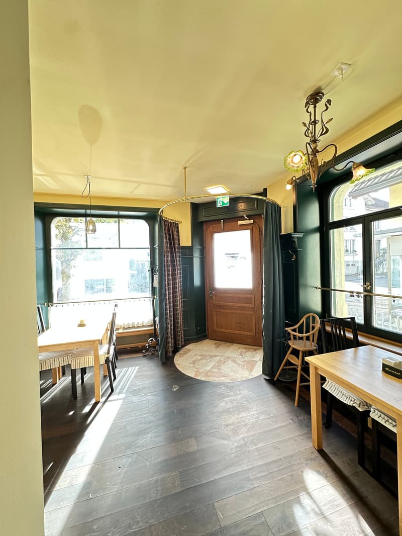 dining area with a wooden table, chairs, yellow walls, green windows, chandeliers, wooden door, view of outside
