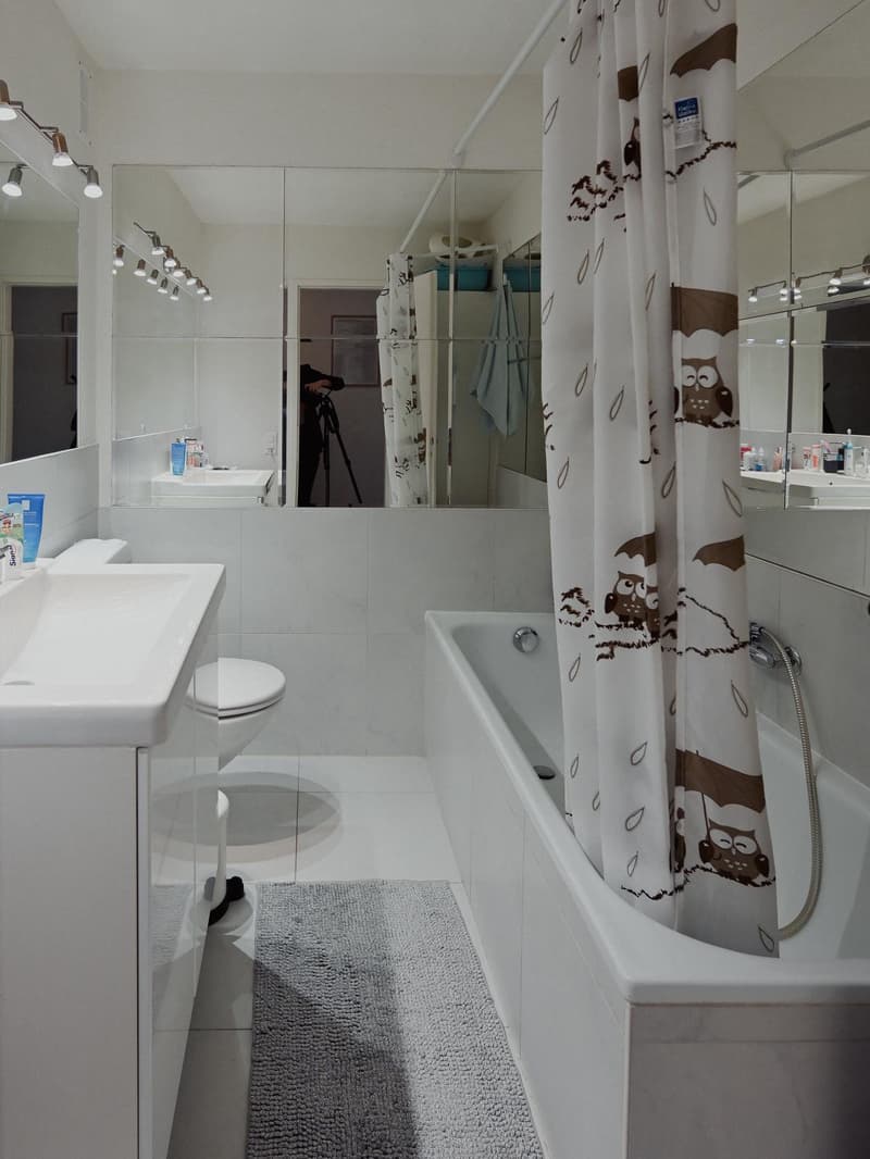 modern bathroom with bathtub, sink, toilet, mirror and shower curtain