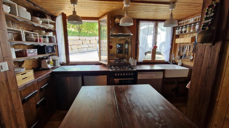 Wooden cabinets, wooden table, stainless steel appliances, kitchen sink, wooden ceiling, open windows