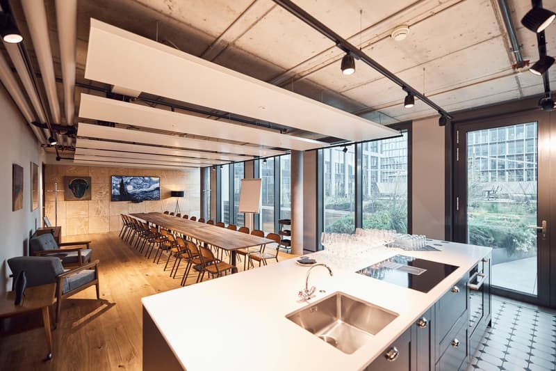 large room, long table, chairs, lamps, sink, counter, large windows