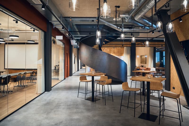 modern styled with wooden flooring, glass walls, large tables, metal and wooden chairs, pendant lights, large spiral staircase