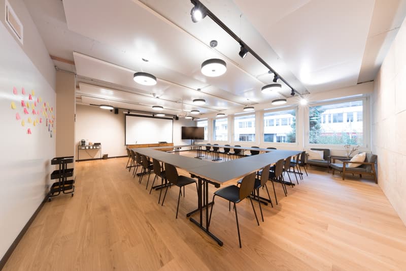 Meeting room, long tables, U-shaped seating, whiteboard, windows with city view, track lighting