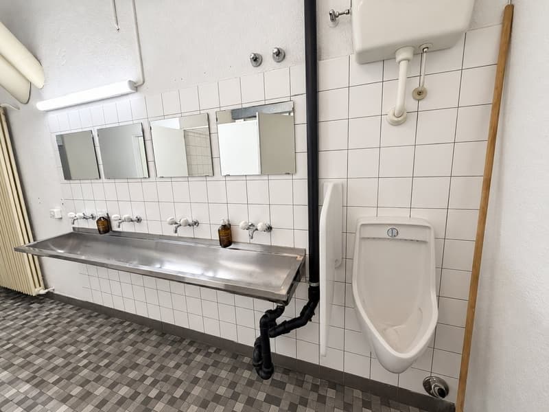 Heller_industrieller_Sanitaerraum_mit_Edelstahlwaschbecken.png