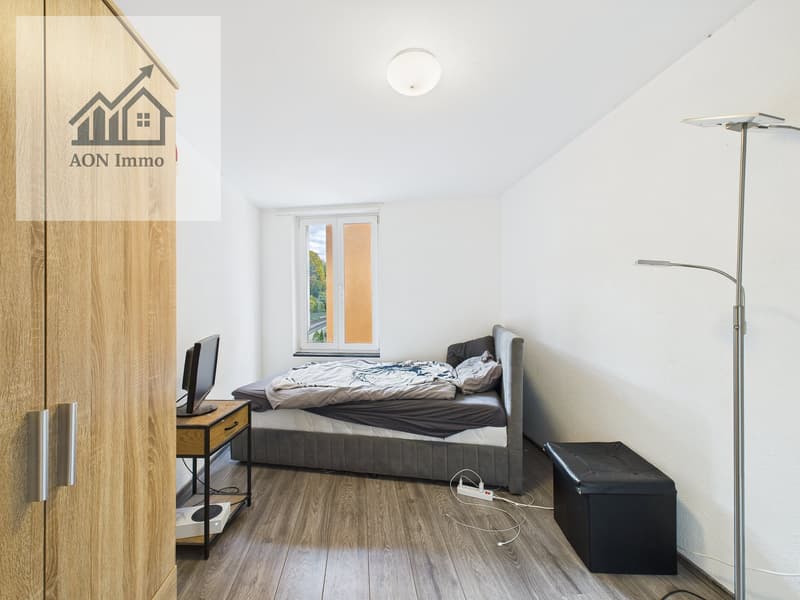 Bedroom with bed, desk, monitor, wooden cabinet, floor lamp, power outlet, storage box, window