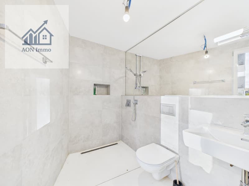 modern bathroom with white tiles, shower, toilet, sink, and mirror