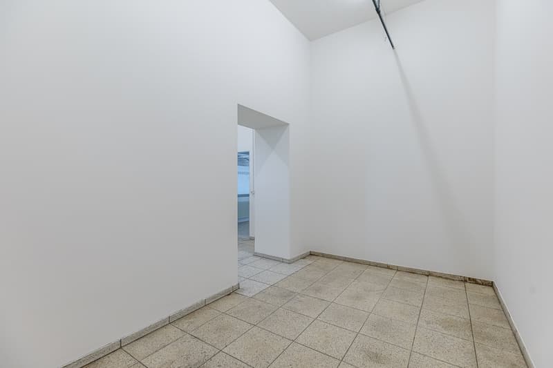 Empty room with white walls, granite tile flooring, and a doorway leading to another room.