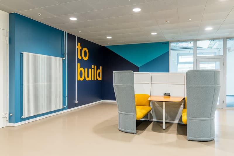 blue walls, white ceiling, yellow text 'to build', large white radiator, desk with chairs, modern office furniture