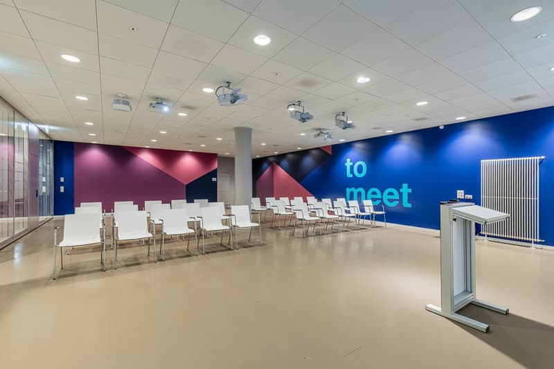 Empty meeting room with chairs and lectern, blue and purple walls, white ceiling