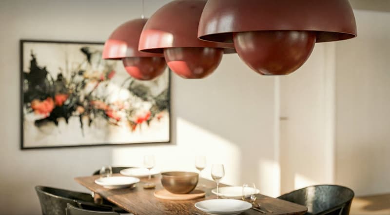Dining room with wooden table, chairs, and red pendant lights