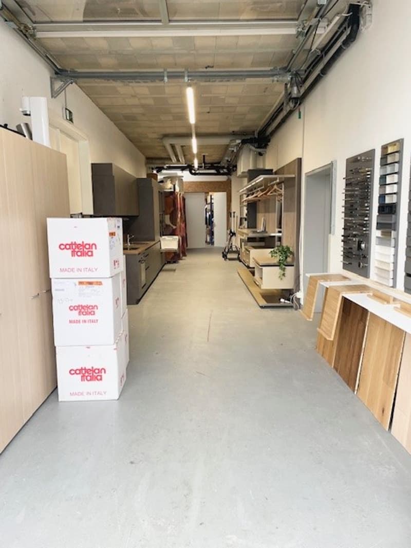 An empty showroom with stacks of boxes, wooden planks, cabinets, sinks, and shelves