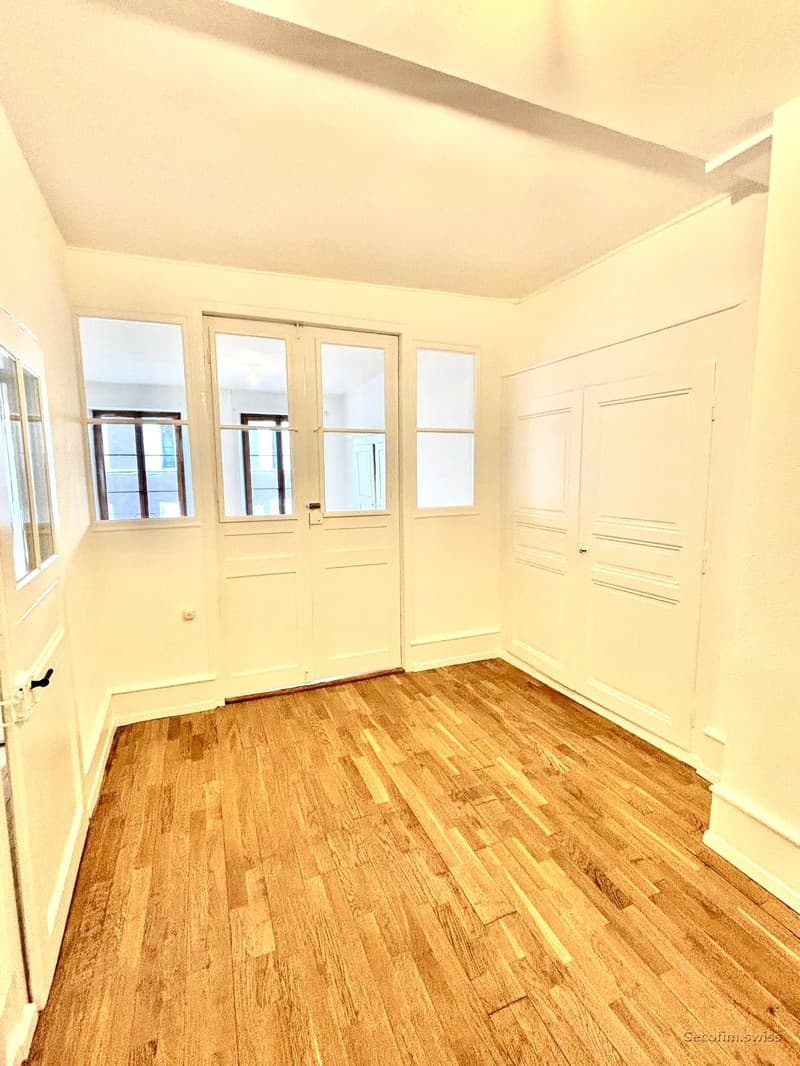 Empty room with wooden floors, white walls, 3 windows, sliding glass doors, power outlets, and built-in closets.