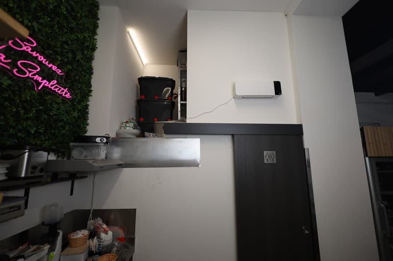 kitchen, pink neon sign, stack of storage boxes, open shelves, stainless steel appliances, black door