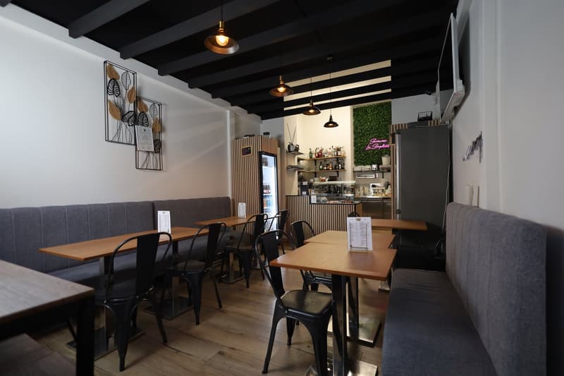 wooden floors, grey benches, multiple tables, black chairs, modern lamps, white walls