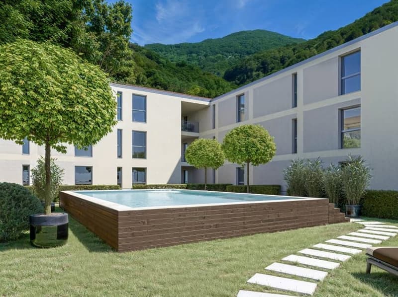 White building with windows, small pool, grassy yard, trees, paved pathway, potted plants, mountains in the background