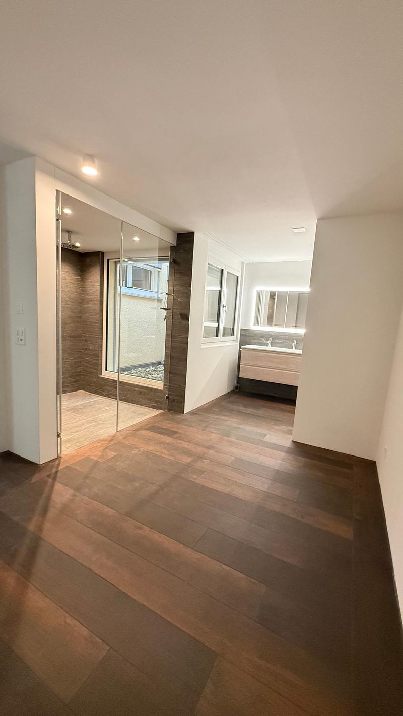 Modern bathroom with walk-in shower, double sink vanity, large mirror, hardwood floors, recessed lighting, sliding glass door.