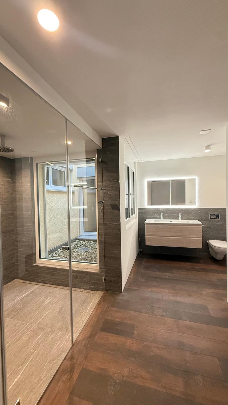 wooden floor, double sink, walk-in shower, glass door, window, mirror, toilet